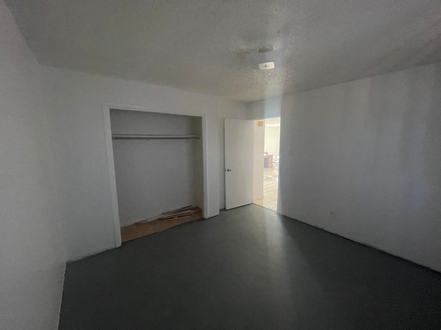 unfurnished bedroom featuring a closet, a textured ceiling, and light tile floors