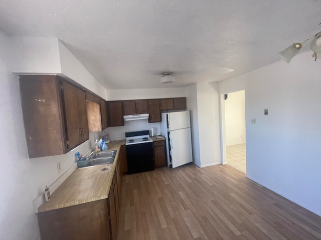 kitchen with white appliances, sink, dark brown cabinets, light hardwood / wood-style floors, and a textured ceiling