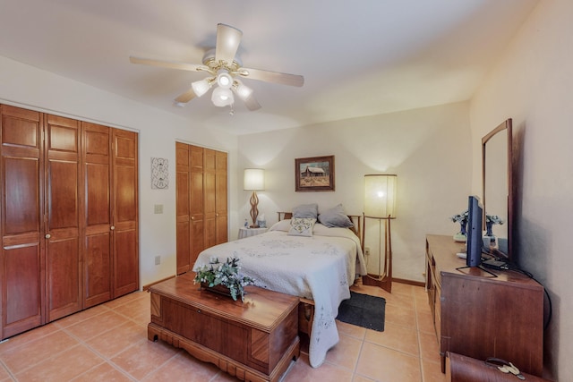 bedroom featuring multiple closets, ceiling fan, baseboards, and light tile patterned floors