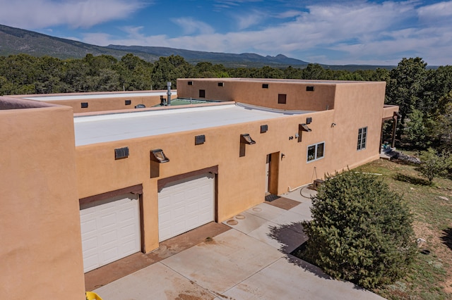 exterior space with a mountain view, driveway, and stucco siding