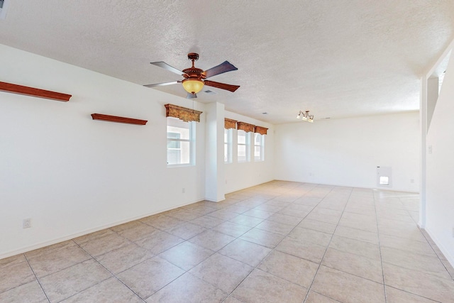 spare room featuring light tile floors, ceiling fan, and a textured ceiling