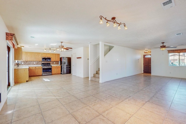 unfurnished living room featuring ceiling fan, sink, and light tile flooring