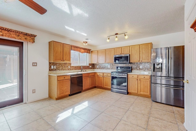 kitchen with ceiling fan, light tile floors, appliances with stainless steel finishes, backsplash, and track lighting