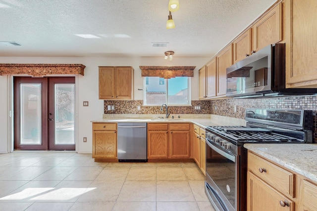 kitchen featuring backsplash, a textured ceiling, appliances with stainless steel finishes, and french doors