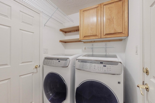 laundry area with a textured ceiling, cabinets, and washer and clothes dryer