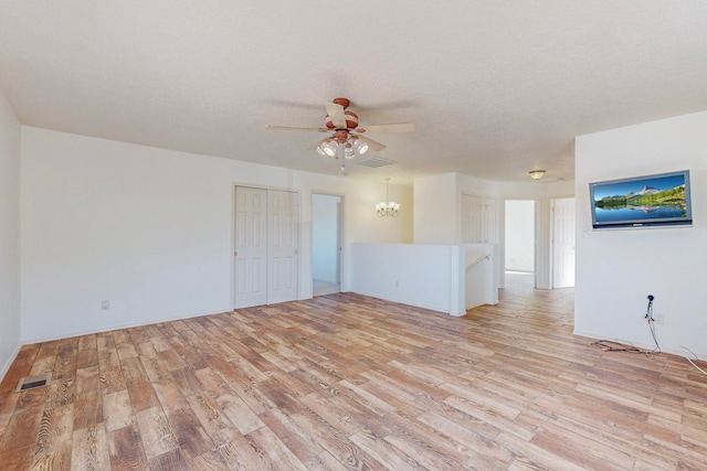 unfurnished room featuring a textured ceiling, light hardwood / wood-style floors, and ceiling fan with notable chandelier