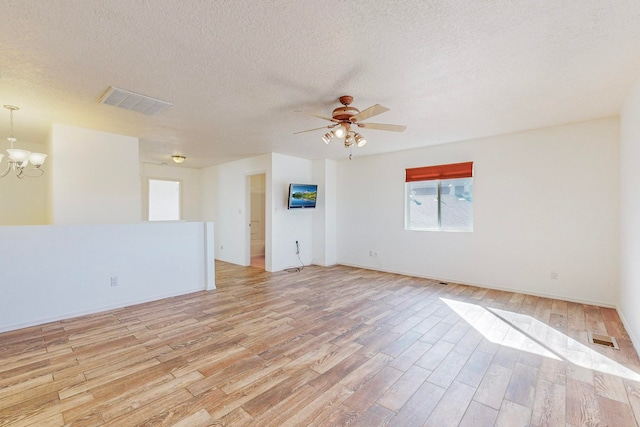 unfurnished room featuring a textured ceiling, ceiling fan with notable chandelier, and light hardwood / wood-style floors