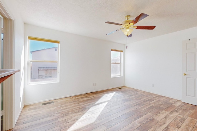 empty room with a textured ceiling, ceiling fan, and light hardwood / wood-style flooring