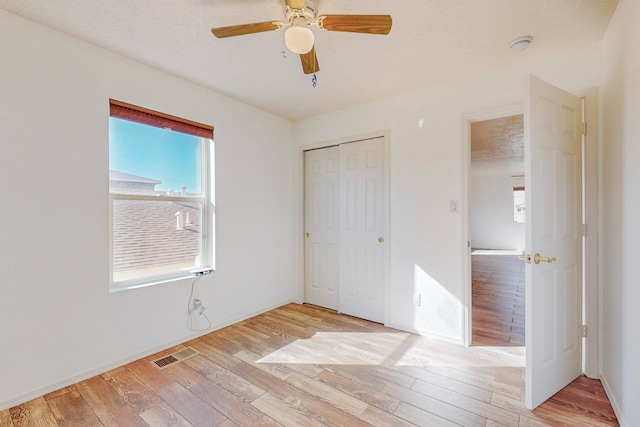 unfurnished bedroom with ceiling fan, light hardwood / wood-style flooring, and a closet