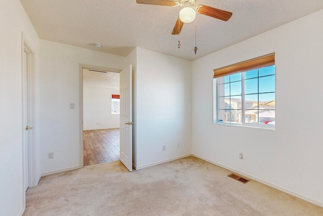 unfurnished bedroom with light carpet, a textured ceiling, and ceiling fan