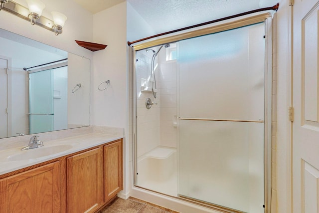 bathroom featuring a shower with door, tile flooring, a textured ceiling, and vanity