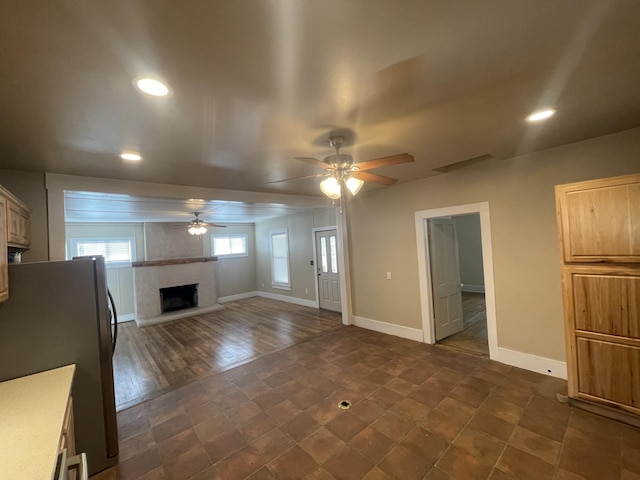 unfurnished living room featuring a large fireplace and ceiling fan