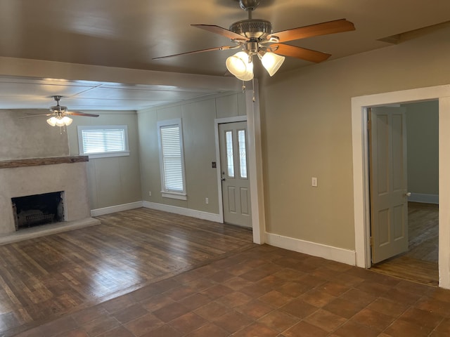 unfurnished living room with ceiling fan, a high end fireplace, and dark hardwood / wood-style flooring