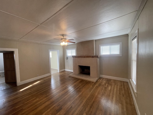 unfurnished living room featuring a wealth of natural light, wood-type flooring, a premium fireplace, and ceiling fan