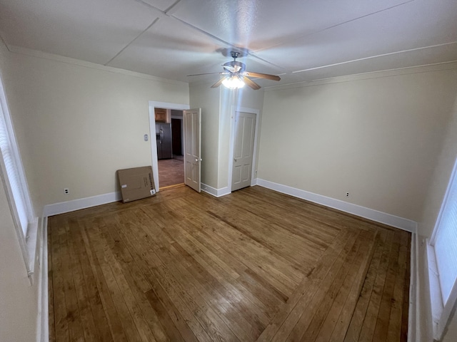 unfurnished bedroom with crown molding, hardwood / wood-style flooring, ceiling fan, and stainless steel refrigerator with ice dispenser