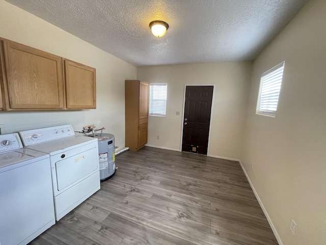 clothes washing area with water heater, cabinets, light hardwood / wood-style floors, washer and dryer, and a textured ceiling