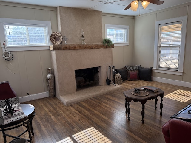 living room featuring a fireplace, dark wood-type flooring, and ceiling fan