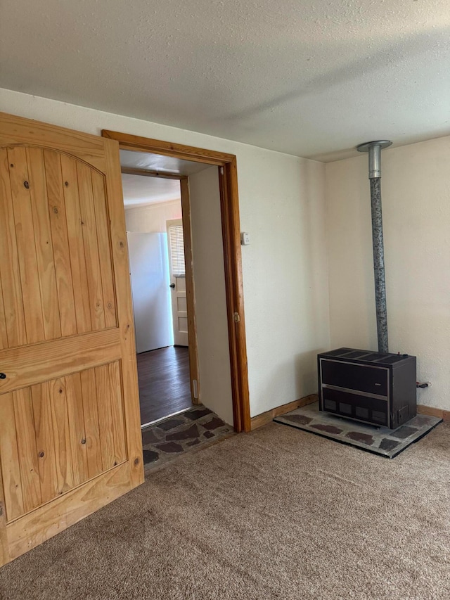 unfurnished living room featuring a wood stove, dark colored carpet, and a textured ceiling