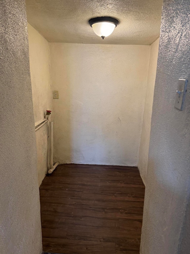 hallway with a textured ceiling and dark hardwood / wood-style flooring