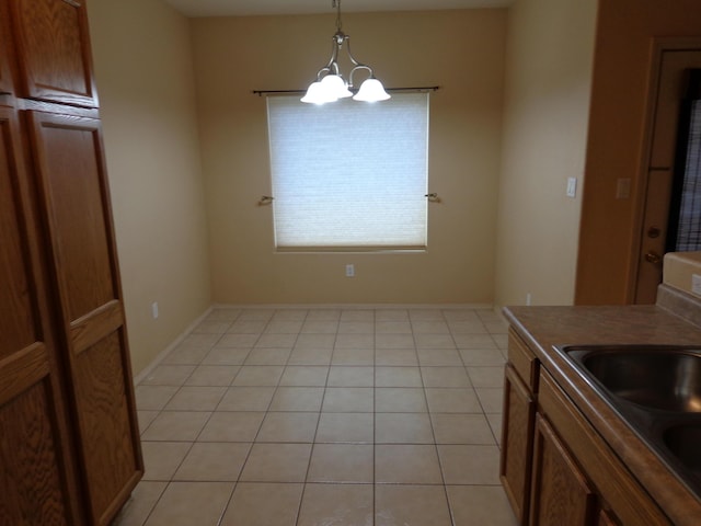 kitchen with pendant lighting, sink, light tile patterned flooring, and an inviting chandelier