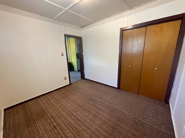 unfurnished bedroom with a closet and dark carpet