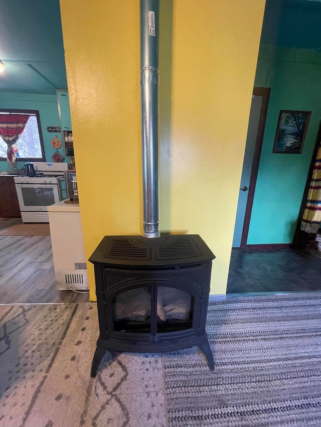 interior details featuring white gas range oven, wood-type flooring, and a wood stove