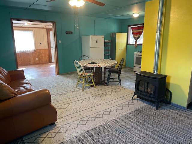 dining space featuring wood-type flooring, a wood stove, and ceiling fan