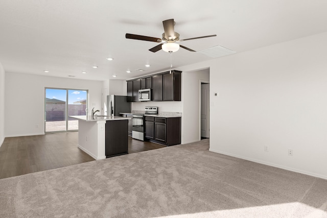 kitchen featuring dark hardwood / wood-style floors, ceiling fan, appliances with stainless steel finishes, sink, and an island with sink