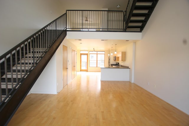 324 Broadway Blvd NE, Albuquerque, NM 87102 - unfurnished living room featuring stairway, wood finished floors, and a towering ceiling