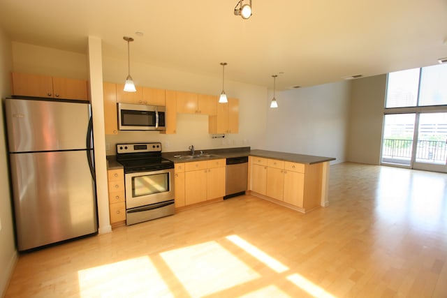 kitchen with light brown cabinets, pendant lighting, stainless steel appliances, and sink