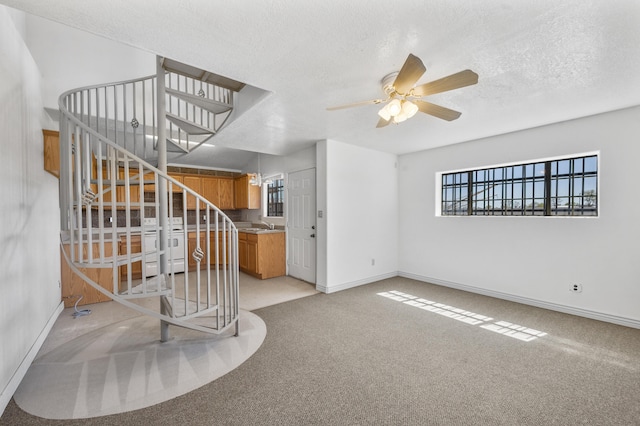 interior space featuring light colored carpet, ceiling fan, and a textured ceiling