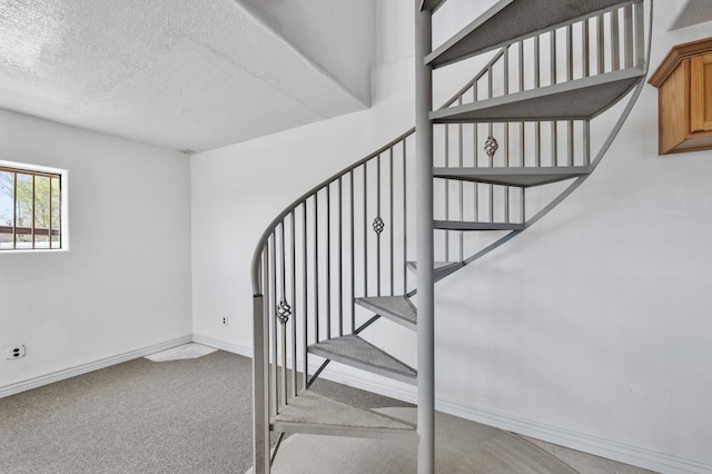 stairway featuring light carpet and a textured ceiling