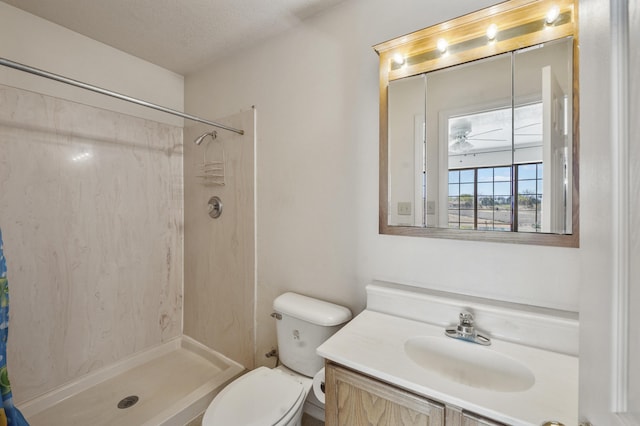 bathroom featuring oversized vanity, a shower with shower curtain, toilet, ceiling fan, and a textured ceiling