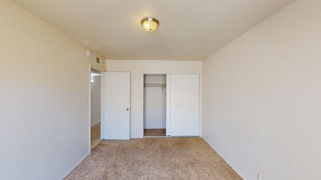 unfurnished bedroom with light carpet, a closet, and a textured ceiling