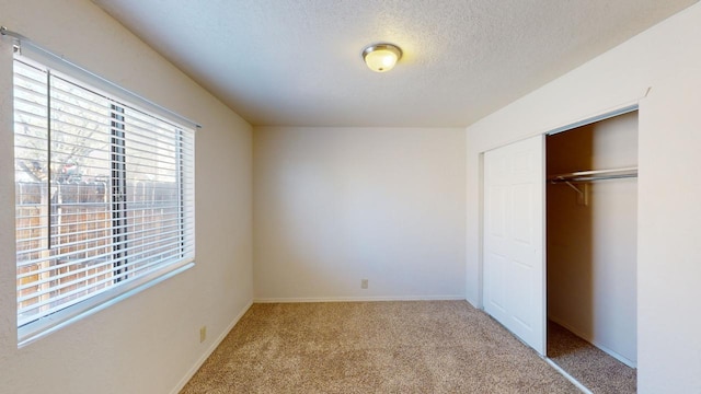 unfurnished bedroom with a textured ceiling, light carpet, and a closet