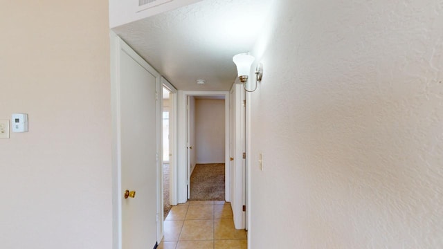 hall featuring light tile patterned floors and a textured ceiling