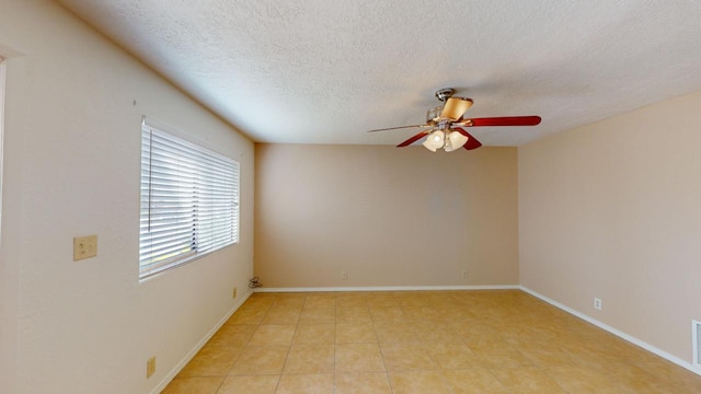 spare room featuring light tile patterned floors, a textured ceiling, and ceiling fan