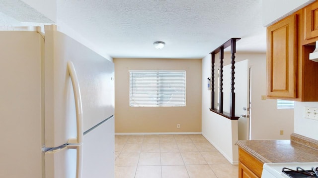 kitchen with a textured ceiling, white refrigerator, and light tile patterned floors