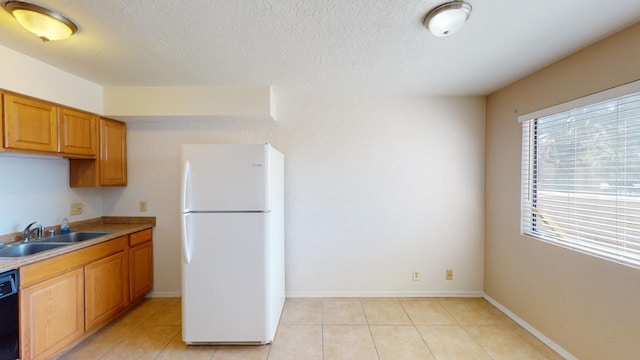 kitchen with dishwasher, light tile patterned floors, white fridge, and sink