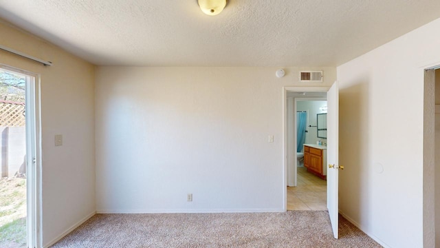 spare room featuring light carpet and a textured ceiling