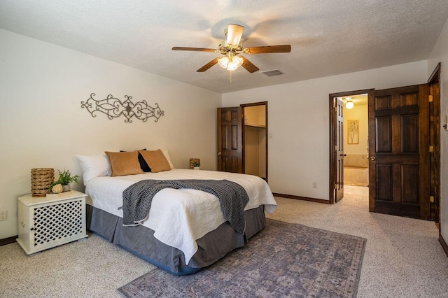 bedroom with a textured ceiling, ceiling fan, connected bathroom, and carpet flooring