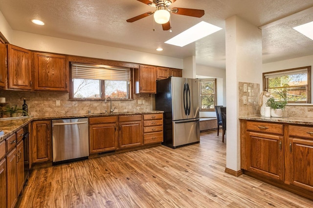 kitchen featuring sink, light hardwood / wood-style flooring, backsplash, and stainless steel appliances