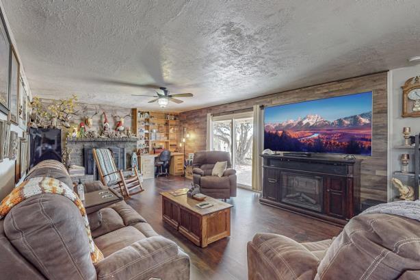 living room featuring dark hardwood / wood-style flooring, ceiling fan, wooden walls, and a textured ceiling