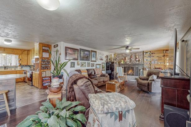 living room with a fireplace, ceiling fan, hardwood / wood-style flooring, and a textured ceiling