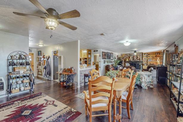 dining area with a fireplace, ceiling fan, dark wood-type flooring, and a textured ceiling