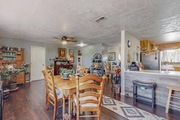 dining room with a textured ceiling, ceiling fan, and dark wood-type flooring