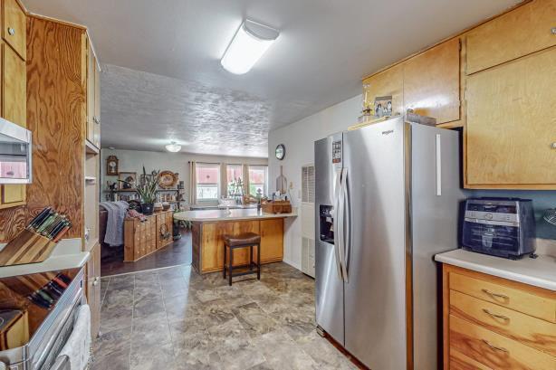 kitchen with stove, tile floors, kitchen peninsula, a breakfast bar area, and stainless steel fridge with ice dispenser