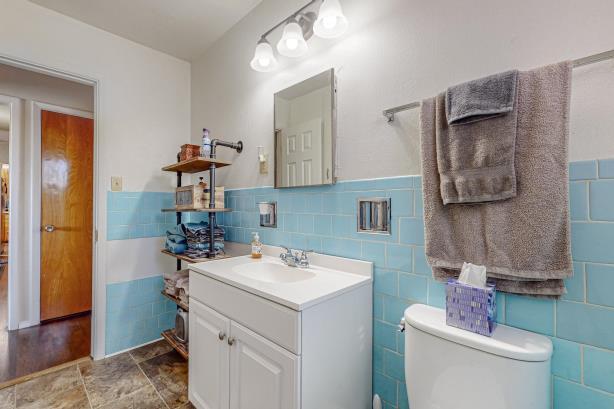 bathroom featuring tile flooring, vanity, toilet, and tile walls