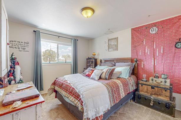 carpeted bedroom featuring brick wall