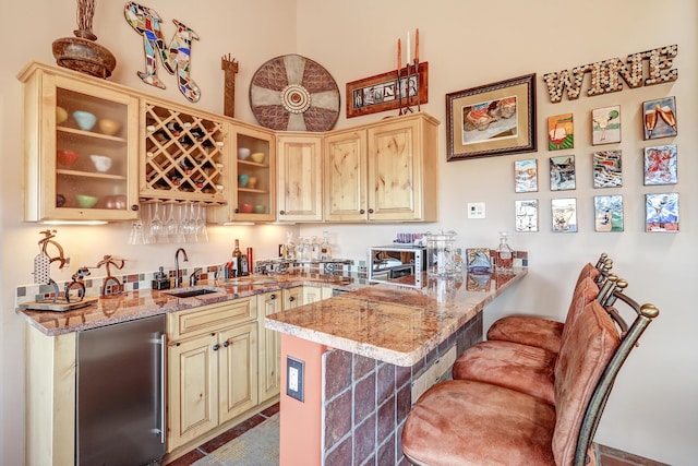 kitchen with light stone counters, a kitchen breakfast bar, and refrigerator